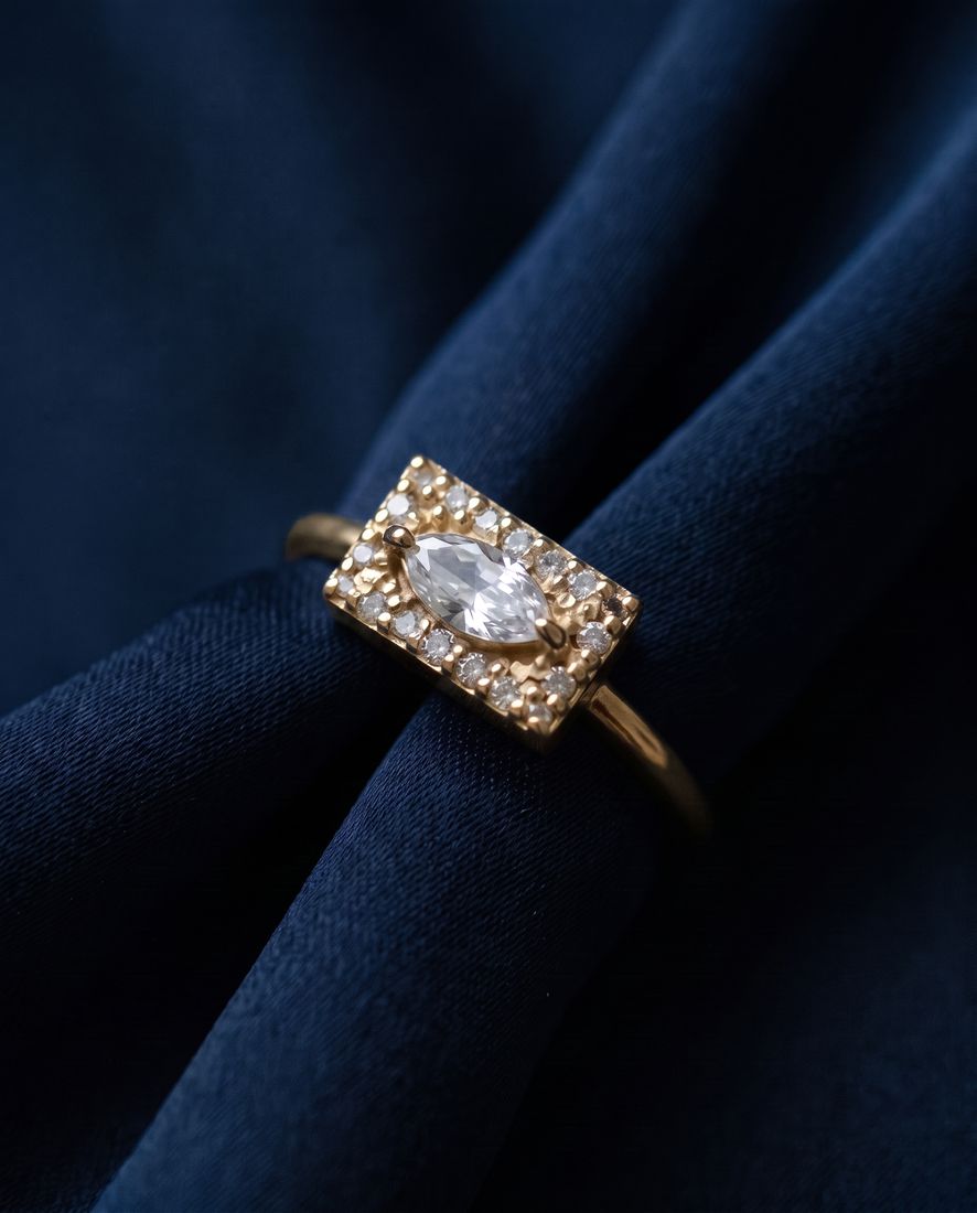 Gold ring with a flat rectangular panel set with a marquise lab-grown diamond and pavé stones