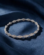 Solid gold bracelet of faceted rhombus links pavé-set with small round lab-grown diamonds, shown on a plain ground