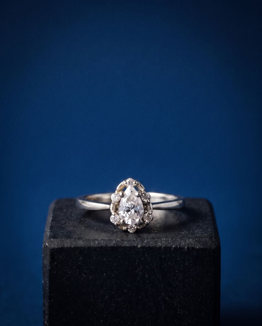 Gold ring with a pear-shaped lab-grown diamond surrounded by a halo of round stones