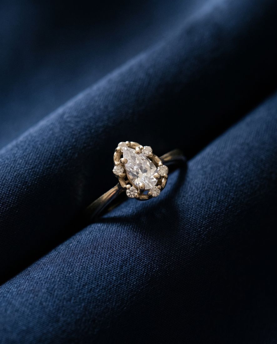 Gold ring with a pear-shaped lab-grown diamond surrounded by a halo of round stones