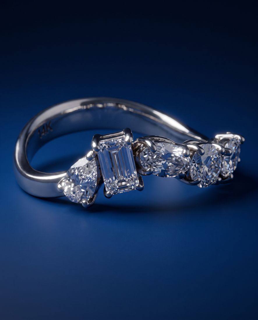 Gold ring set with five lab-grown diamonds in five different cuts along the band