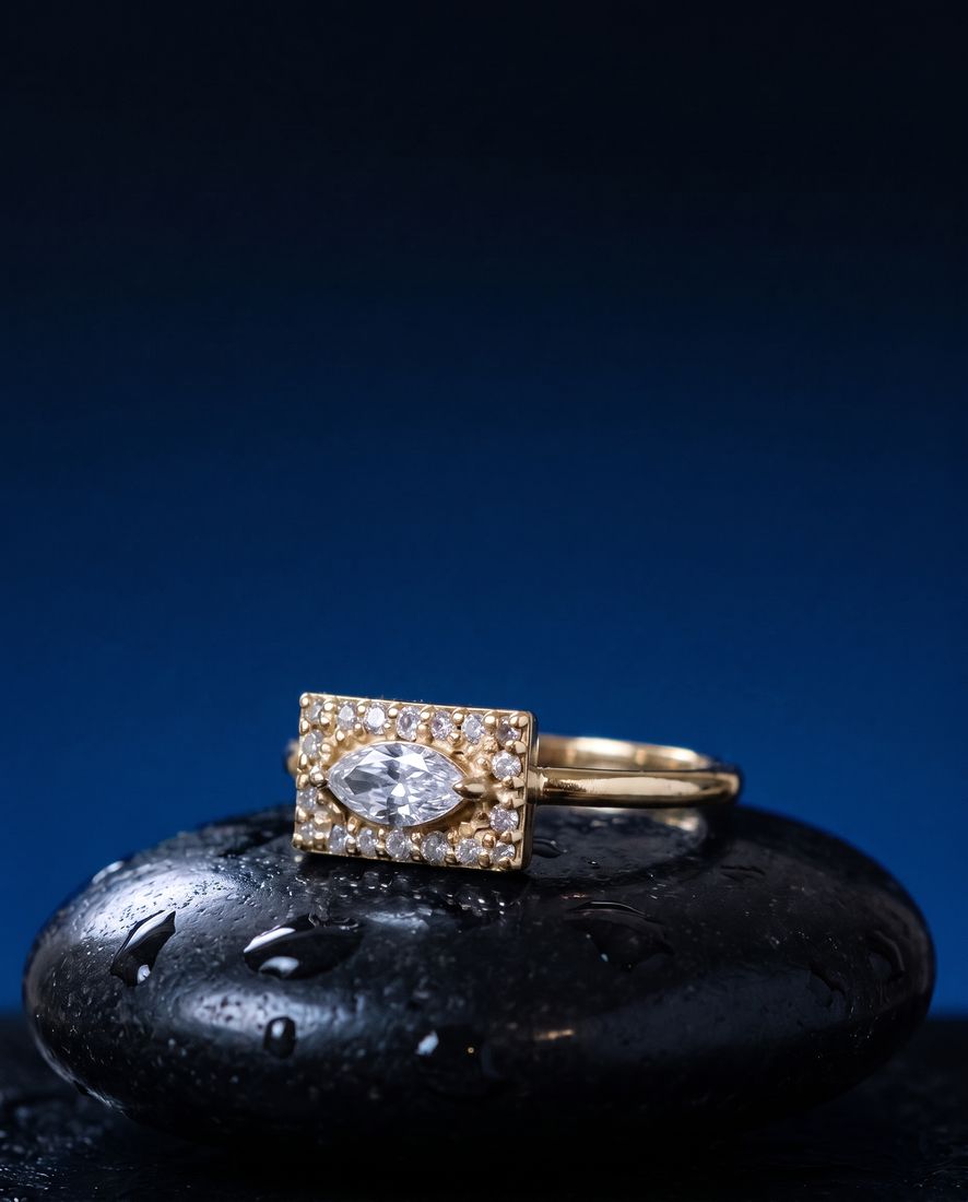 Gold ring with a flat rectangular panel set with a marquise lab-grown diamond and pavé stones