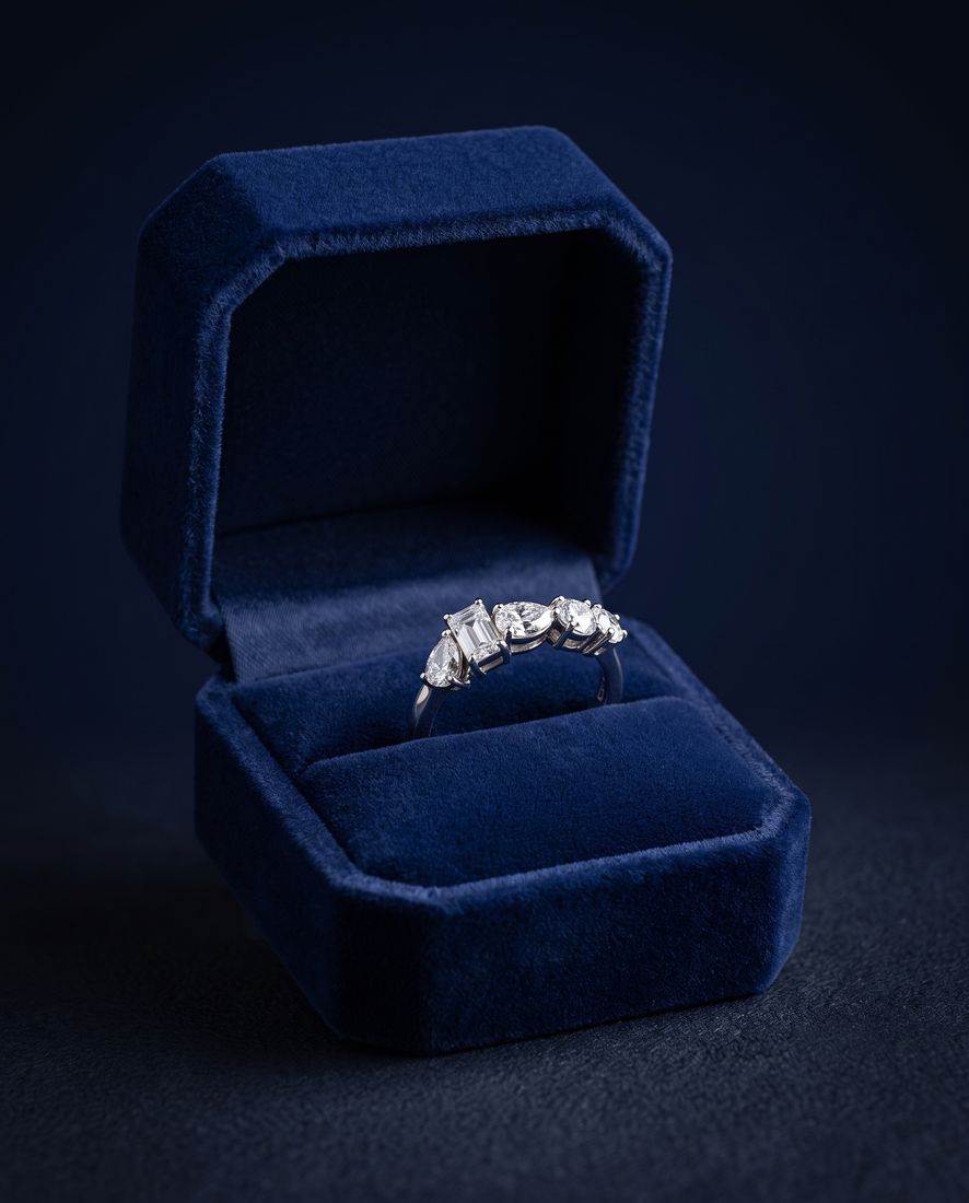 Gold ring set with five lab-grown diamonds in five different cuts along the band