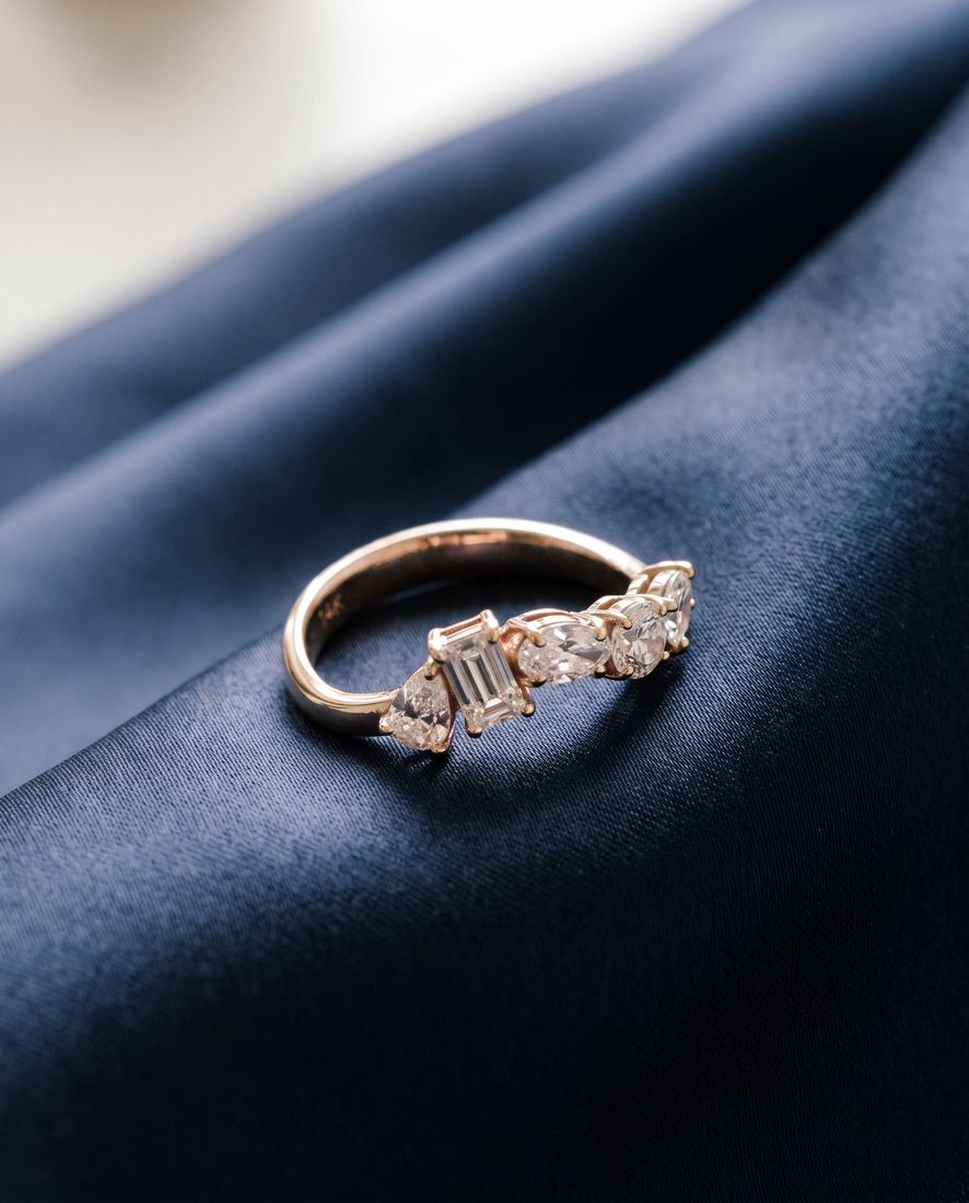 Gold ring set with five lab-grown diamonds in five different cuts along the band