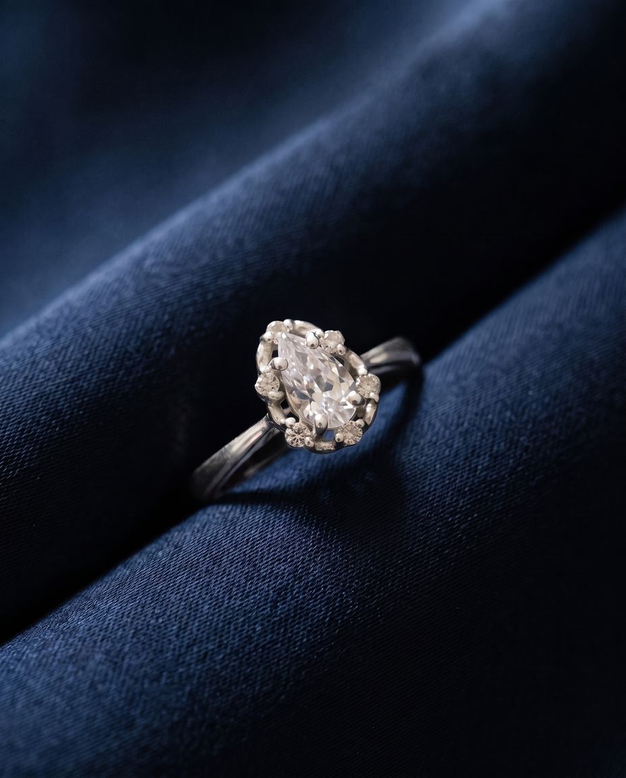 Gold ring with a pear-shaped lab-grown diamond surrounded by a halo of round stones