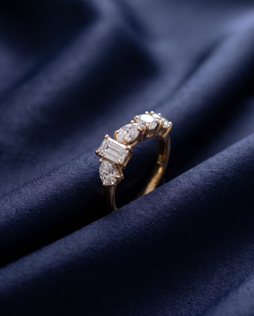Gold ring set with five lab-grown diamonds in five different cuts along the band