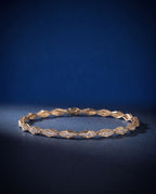 Solid gold bracelet of faceted rhombus links pavé-set with small round lab-grown diamonds, shown on a plain ground
