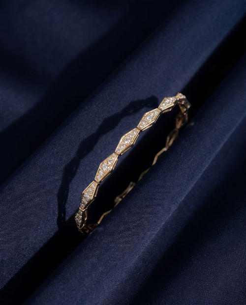 Solid gold bracelet of faceted rhombus links pavé-set with small round lab-grown diamonds, shown on a plain ground