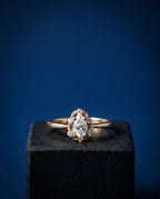 Gold ring with a pear-shaped lab-grown diamond surrounded by a halo of round stones