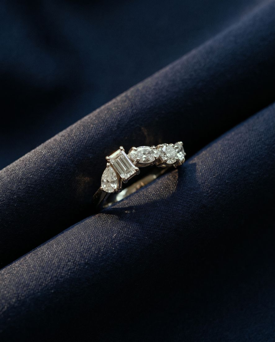Gold ring set with five lab-grown diamonds in five different cuts along the band
