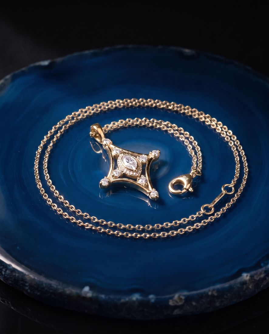 Fine gold chain with a slender pendant set with a marquise lab-grown diamond and small round stones