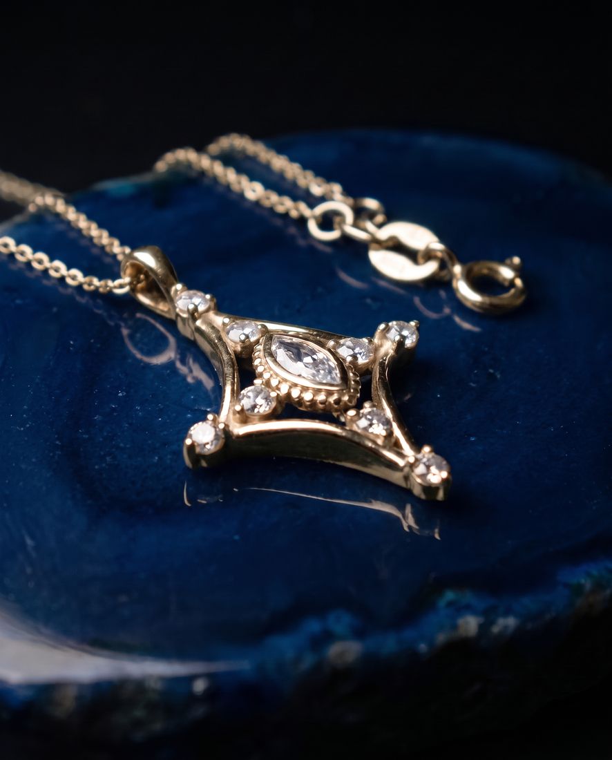 Fine gold chain with a slender pendant set with a marquise lab-grown diamond and small round stones